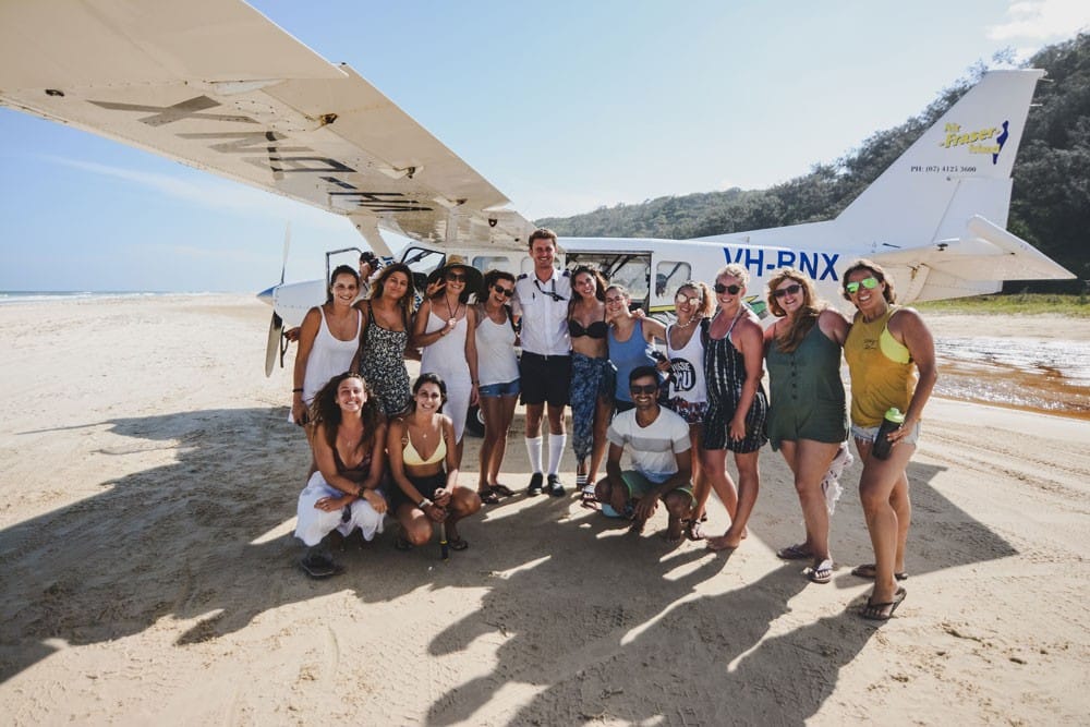 viajar por Australia grupo de estudiantes posando para cámara delante de una avioneta en la isla Fraser de Australia